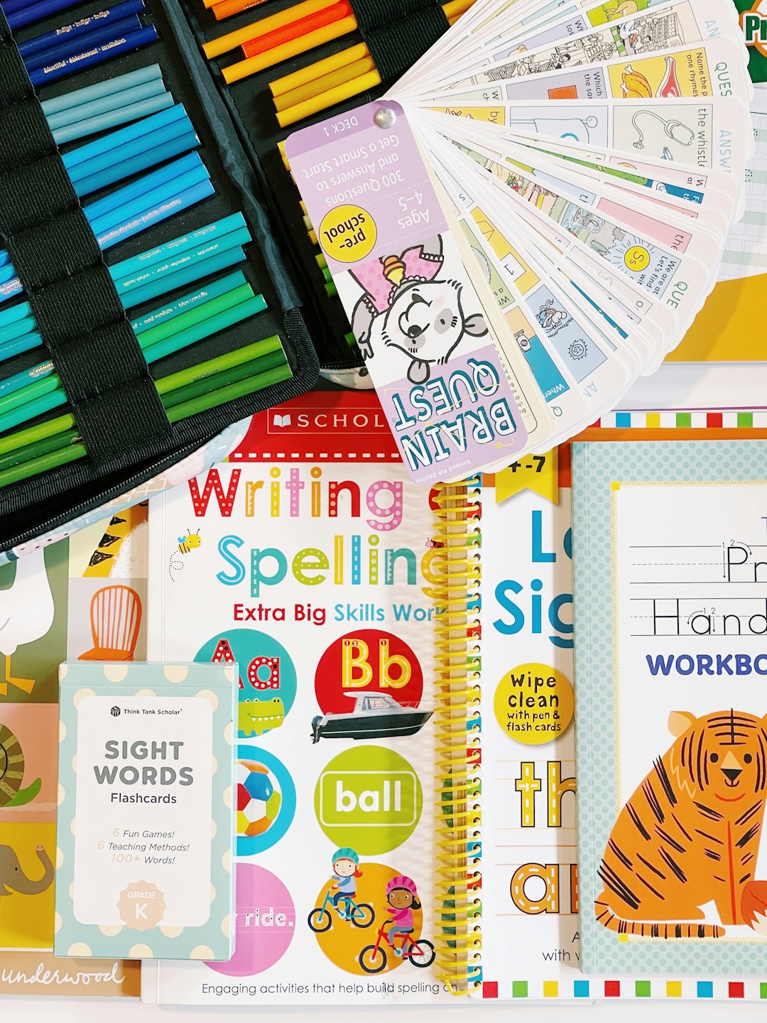 Libros de trabajo educativos y material de arte esparcidos sobre un escritorio.