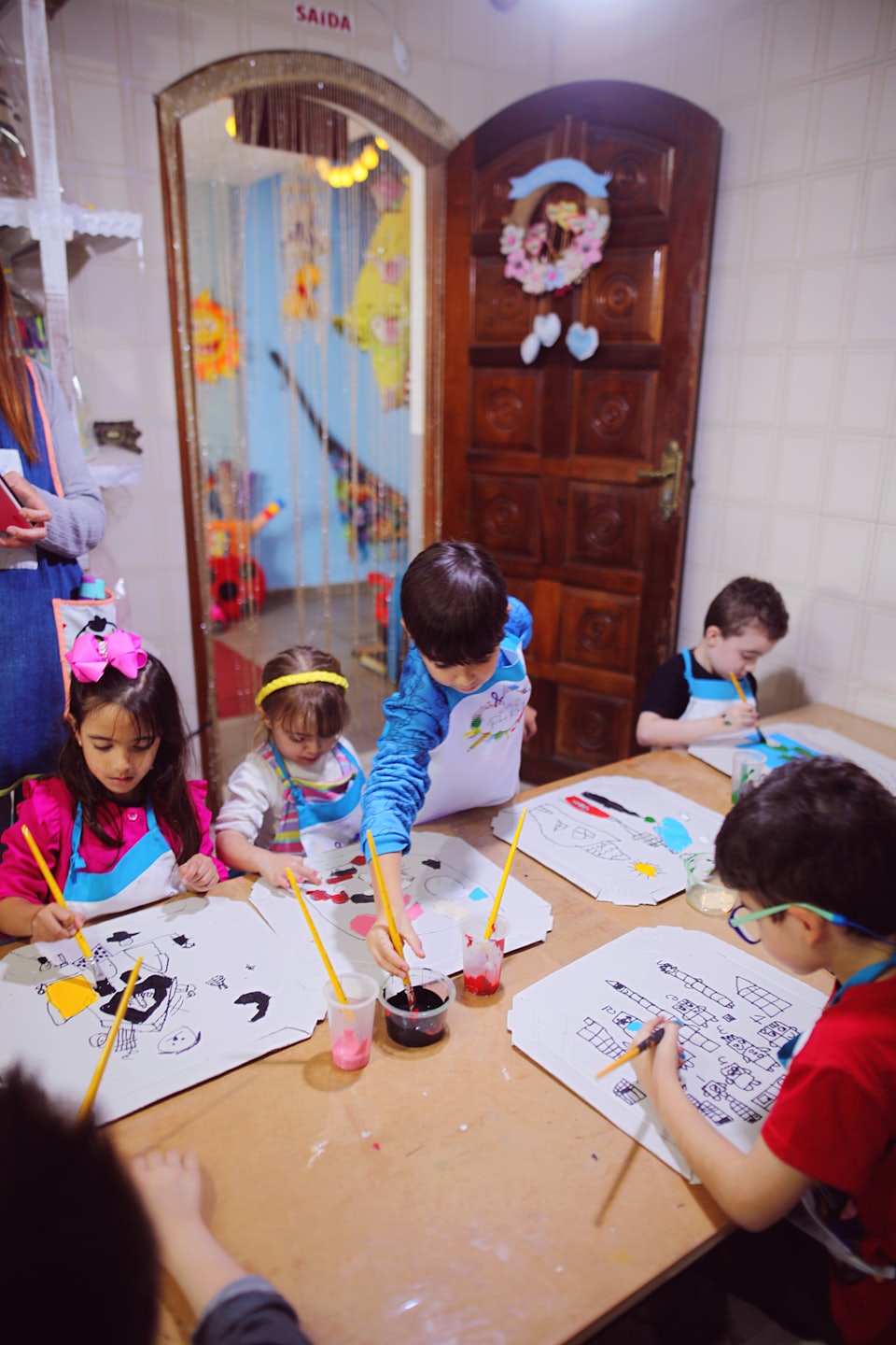 Niños participando en una actividad artística creativa en una mesa de madera.